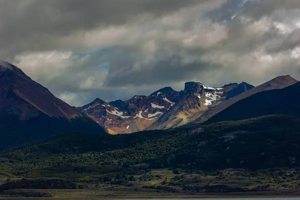 Ushuaia, Arjantin yakınlarında güneş ışığı, dağlar ve bulutlarla dramatik bir manzara.