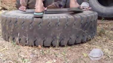 Çocuklar kullanılmış lastikleri kullanarak geleneksel oyunlar oynarlar, zevkle lastiğe atlarlar. 4k görüntü