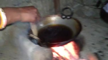 Genç bir kadın mutfaktaki tavada ekmek pişiriyor..