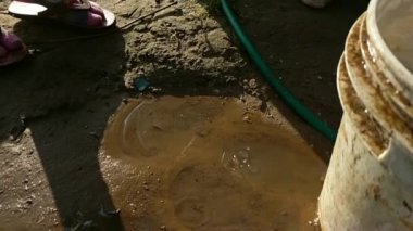 Çiftlik arazisindeki sızdıran bir borudan su damlıyor. Su paslı bir borudan akar. Devamlı su akışı bir borudan geliyor. Ya da yere serilmiş bir su borusundan su fışkırır.