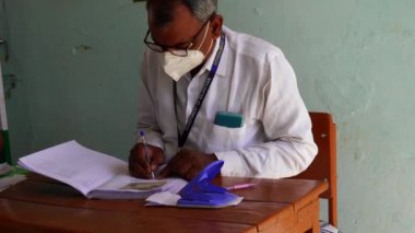 20 Aralık 2022 Chhilawali, Rajasthan, Hindistan. Maskeli müşteriler için sağlık hizmeti uzmanı veya pratisyen hekim belgeleri imzalıyor.