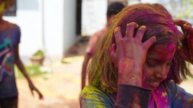 Beautiful young girl posing with exploding pink and yellow Holi powder around her