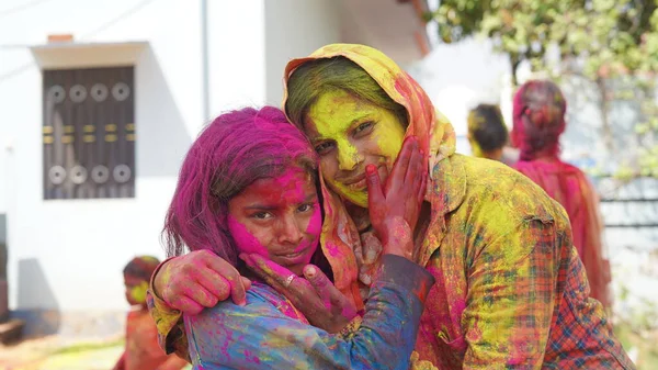 Outdoor image of Asian, Indian happy mother daughter in Indian dress celebrating the Holi festival together with color powder.