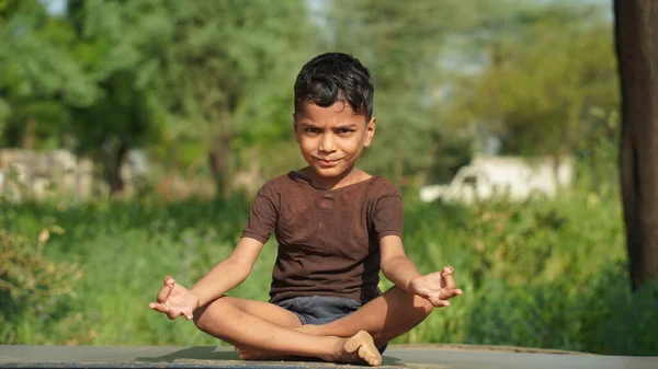 Little boy doing yoga in garden on beautiful nature background.