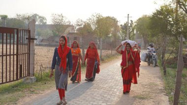 01 Nisan 2023 Jaipur, Rajasthan, Hindistan. Kafalarında çanta taşıyan bir grup Hintli kadın akşamları işten evlerine dönüyorlar, arka planda günbatımı var. Kadınlara odaklan.