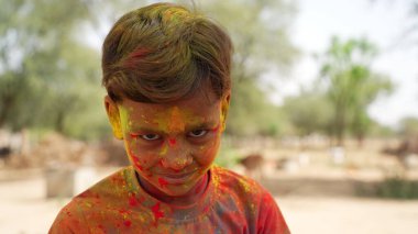 Holi festivalindeki Hintli çocuğun renkli komik yüzü. Holi kutlamaları. Hintli küçük çocuk Holi oynuyor ve surat ifadesi gösteriyor..