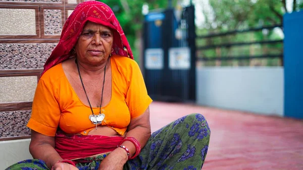 印度老年妇女坐在正门附近看着相机的画像 — 图库照片