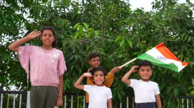 Bağımsızlığı ya da Cumhuriyet Günü 'nü kutlarken, Hintli çocuklar arka planda yeşil ağaçla el sallıyor ve selamlıyorlar..