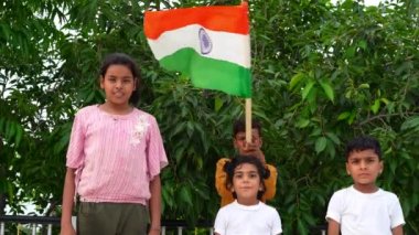 Çatıda koşan ve bayrak sallayan Hintli çocuklar ve yeşil ağaç arka planı. Hindistan Bağımsızlığını ya da Cumhuriyet Günü 'nü kutlayan Hintli çocuk