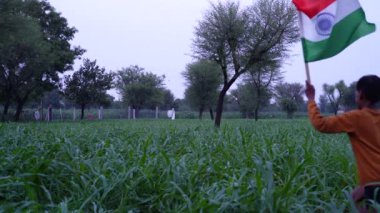 Mutlu Bağımsızlık Günleri. Hindistan 'ın bağımsızlık günü kutlu olsun. Yeşil arka planda Kızılderili bayrağıyla koşan küçük çocuk.