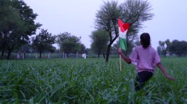 Mutlu Bağımsızlık Günleri. Hindistan 'ın bağımsızlık günü kutlu olsun. Yeşil arka planda Kızılderili bayrağıyla koşan küçük kız.