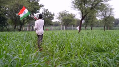 Genç Hintli çiftçi tarla tarlasında Kızılderili bayrağı sallıyor.