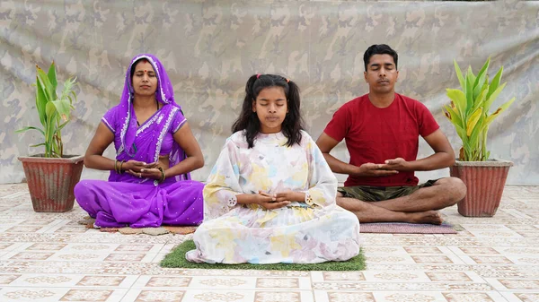Meditation, practicing breathing yoga exercises. Wellness hobby concept,  Happy fit family of young parents and little kids sitting together on floor in lotus positions