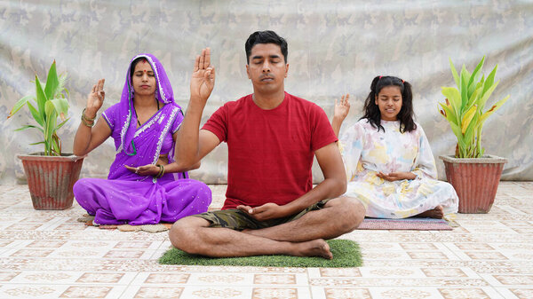 Indian family member doing yoga or meditating while making the Blessing Buddha hand sign.