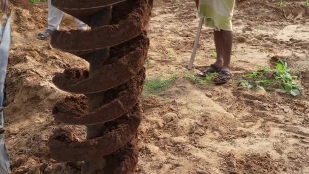 人々はインドの田舎フィールドで掘るトラクターに取付けられた油圧ポストホールオーガーを操作します 農業産業コンセプト — ストック動画