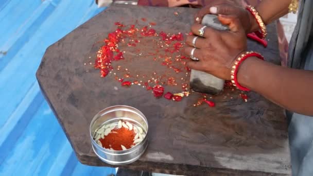 ラジャスターハニーの女性の手は 石で作られたモルタルと害虫を使用して 伝統的なインドのチリソースにチリを粉砕しています — ストック動画