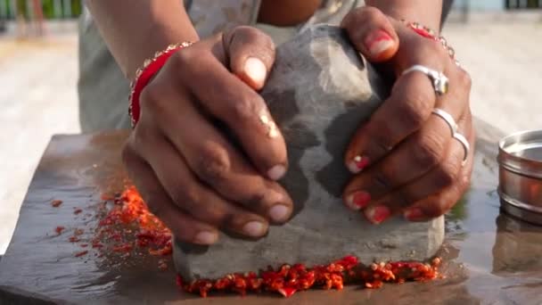 ラジャスターハニーの女性の手は 石で作られたモルタルと害虫を使用して 伝統的なインドのチリソースにチリを粉砕しています — ストック動画