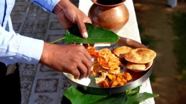 Hintli dindar adam karga kuşunun yemesi için bir yaprağa yemek koydu. Hindu Pitru Paksha veya Shraddha festivali.