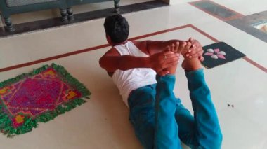 Sağlıklı yaşam tarzı, sağIık ve farkındalık kavramı, genç Hintli adamın evin içinde yerde yoga yapması..