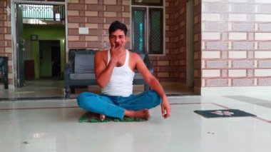 Hintli bir adam evde sağlıklı yaşam tarzı, sağlık ve farkındalık kavramında sabah gözlerini kapayarak burun deliği ya da pranayama yogası yapıyor.