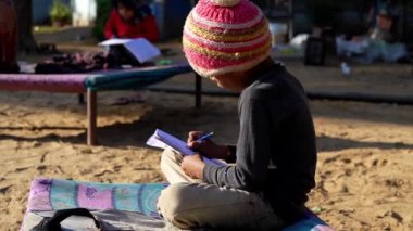 Zavallı Hindistan köylü küçük çocuk elinde kalem ve parkta ödev yapıyor..