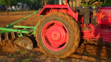 Traktördeki çiftçi toprağı hazırlıyor. Tarım işçiliğinin ilk bahar mevsiminde tohumlama öncesi işlerden biri olarak. 25 Kasım 2023 Jaipur, Rajasthan, Hindistan.