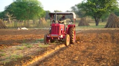 Sonbaharda kırmızı traktör sürüşü, traktörle tarla sürüşü tarla sürüşü tarla sürüşü, tarım çalışmaları. 25 Kasım 2023 Jaipur, Rajasthan, Hindistan.