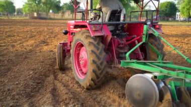 Çok satırlı bir disk harrow, hasat edilen bir buğday tarlası ve mavi bir gökyüzünün arka planına karşı bir tarım traktörüne bağlanıyor. 25 Kasım 2023 Jaipur, Rajasthan, Hindistan.