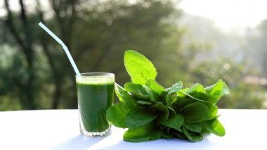 Terasta ıspanaklı ya da palak yapraklı büyük bardakta yeşil meyve suyu..