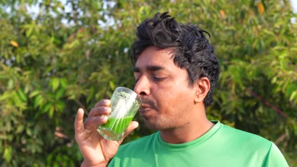 印度男子喝着健康的绿色果汁 年轻的运动衫男子喝着一杯菠菜汁 特写镜头 — 图库视频影像