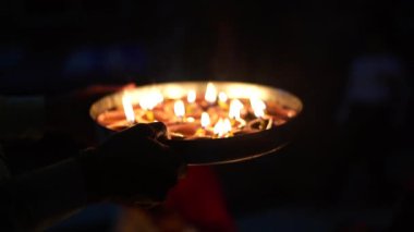 Geleneksel Hindu ışık festivali için zemini toprak diyas yağı mumlarıyla dekore eden insan elinin yavaş çekimini kapat