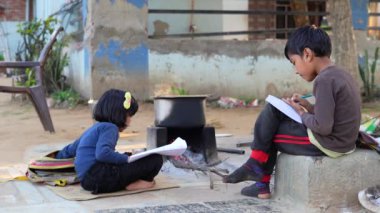 İlkokul öğrencisi kız ve erkek dışarıda ödev yapıyor. Köylü çocuklar kitap okuyor ve kalemle yazıyor. Fakir çocuklar birlikte eğitim öğreniyor.