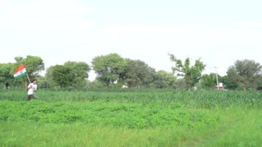 Hintli çocuklar Bağımsızlık Günü 'nü ya da Cumhuriyet Günü' nü kutluyor. Beyaz tişörtlü ve Kızılderili bayrağı taşıyan çocuklar. Asya kırsalının görüntüleri