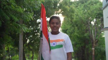 Ulusal bayrak logosu tasarımı giyen Hintli köylüler tişört basıp tutuyorlar, arka planda yeşillik olan Tricolor 'la el sallıyorlar, Bağımsızlık Günü' nü veya Cumhuriyet Günü 'nü kutluyorlar.
