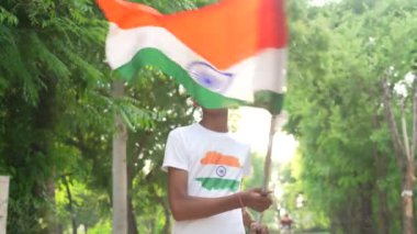 Ulusal bayrak logosu tasarımı giyen Hintli köylüler tişört basıp tutuyorlar, arka planda yeşillik olan Tricolor 'la el sallıyorlar, Bağımsızlık Günü' nü veya Cumhuriyet Günü 'nü kutluyorlar.