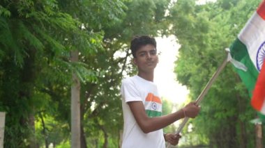 Ulusal bayrak logosu tasarımı giyen Hintli köylüler tişört basıp tutuyorlar, arka planda yeşillik olan Tricolor 'la el sallıyorlar, Bağımsızlık Günü' nü veya Cumhuriyet Günü 'nü kutluyorlar.