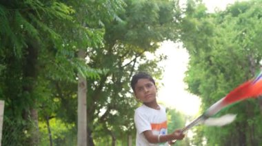 Ulusal bayrak logosu tasarımı giyen Hintli köylüler tişört basıp tutuyorlar, arka planda yeşillik olan Tricolor 'la el sallıyorlar, Bağımsızlık Günü' nü veya Cumhuriyet Günü 'nü kutluyorlar.