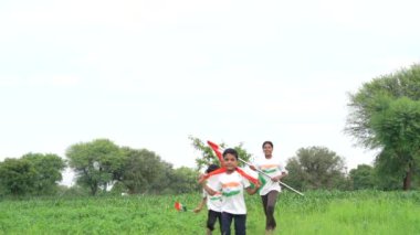 Ulusal bayrak logosu tasarımı giyen Hintli köylüler tişört basıp tutuyorlar, arka planda yeşillik olan Tricolor 'la el sallıyorlar, Bağımsızlık Günü' nü veya Cumhuriyet Günü 'nü kutluyorlar.