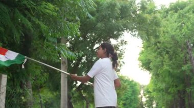 Ulusal bayrak logosu tasarımı giyen Hintli köylüler tişört basıp tutuyorlar, arka planda yeşillik olan Tricolor 'la el sallıyorlar, Bağımsızlık Günü' nü veya Cumhuriyet Günü 'nü kutluyorlar.