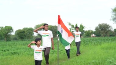 Ulusal bayrak logosu tasarımı giyen Hintli köylüler tişört basıp tutuyorlar, arka planda yeşillik olan Tricolor 'la el sallıyorlar, Bağımsızlık Günü' nü veya Cumhuriyet Günü 'nü kutluyorlar.