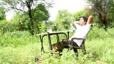 Hintli genç çocuk dizüstü bilgisayarla parkta tek başına oturuyor ve uzaktan kumandalı işleri başarıyor. Çocuk kendi dizüstü bilgisayarının projelerini kendi bitiriyor. Evden Çalışma Konsepti.