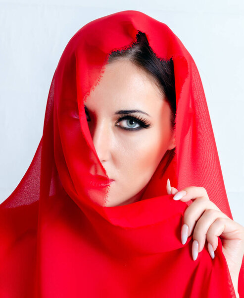 Portrait of a girl in a veil. A red veil covers the face.