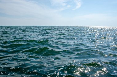 Mavi gökyüzüne karşı deniz dalgaları. Suyun yanındaki iskele..