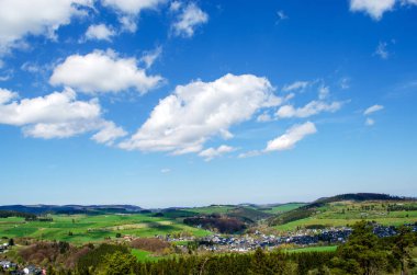 Yazın mavi güzel gökyüzüne karşı beyaz düzensiz bulutlar. Dağları ve ormanı olan Almanya köyleri.