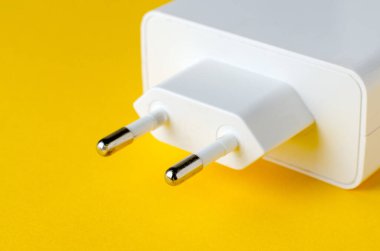 Sarı arkaplanda beyaz elektrik prizi adaptörü, yakın çekim görüntüsü