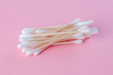 Pastel pembe arka planda beyaz pamuklu çubuklar.