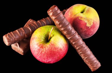 Meyve Çikolataya Karşı Sağlıklı Bir Seçim. Taze meyveler ve siyah arka planda cazip çikolatalar.. 