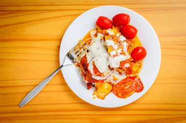 Yumurtalı sağlıksız kızarmış yemek, domates, domuz yağı ve tahta zeminde mayonez.