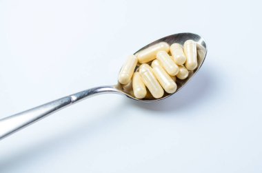 Beyaz arkaplanda renkli kapsüllü kaşık