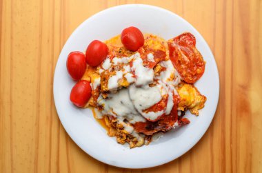 Beyaz tabakta domatesli yumurta ve mayonez sağlıksız bir yiyecek.